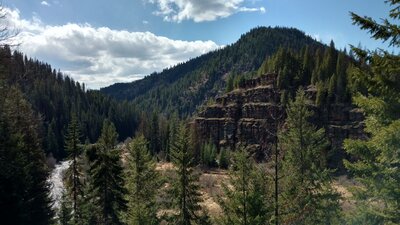 The Coeur d'Alene River (left) shimmers as it flows through the forested mountains and their impressive rock outcroppings.