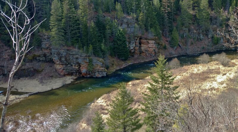 The beautiful Coeur d'Alene River with it rapids, as it bounces off colorful cliffs below.