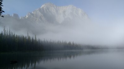Morning mist dispersing reveals Mount Aosta and Lower Elk Lake, seen from the shoreline at the campground.