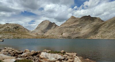 Photo Pass (left center) in the distance on the Continental Divide, is seen from the south end of Bewmark Lake. An unnamed peak (center) and Odyssey Peak (right center) also on the Divide.