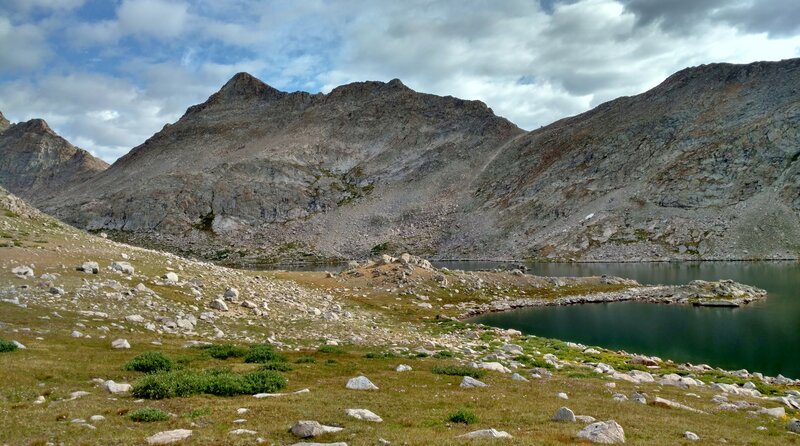 Odyssey Peak (12,062 ft.) on the Continental Divide, rises above Bewmark Lake and its surrounding alpine meadows.