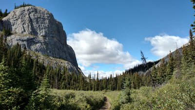 Impressive rock walls rise above the trail as it travels through the meadows of Eagles Nest Pass, 6,201 ft. Eagles Nest Pass is a gap in the Persimmon Range.