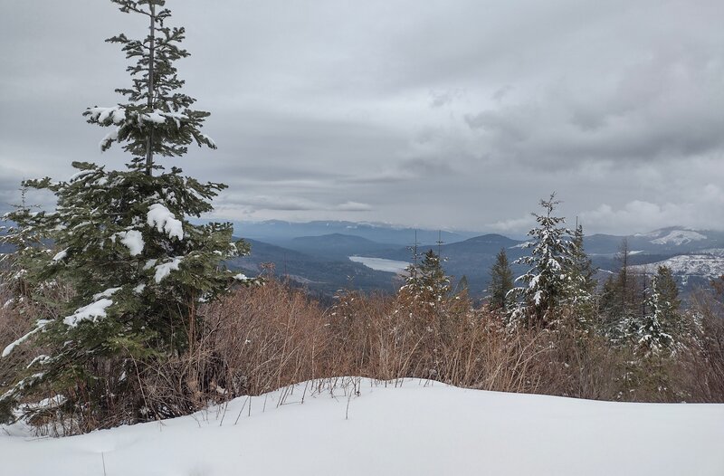 Twin Lakes below (center) nestled in the nearby, forested Rathdrum hills, with more mountains in the distance, on a gray, winter February afternoon. Seen looking east from a nice viewpoint along Upper Outer Limits.