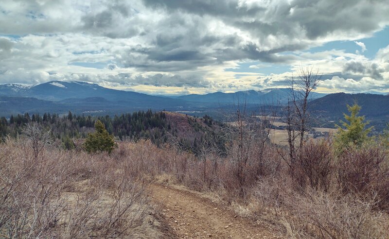 Mountains surround the flat farmlands below, in a typical northern Idaho landscape, here in Priest River country. Seen from high on Peewee Peak's John Wayne Trail.