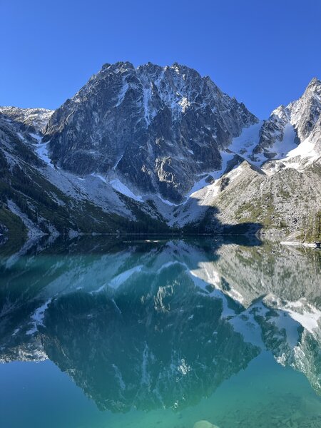Lake turning from blue to emerald green as the sun rises over the mountain ridge.
