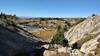 From high on Doubletop Mountain Trail, one can see all the way to the flat lands, to the west. Nearby, typical of this area, is the rocky, grassy terrain dotted with trees and a cute lake.