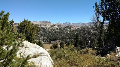 The highest peaks of the Wind River Range are in the distance, rising above closer hills. Seen looking east from high on Doubletop Mountain.