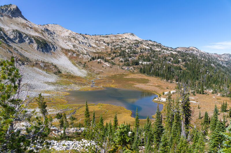 Looking down from the switchbacks above Upper Lake at 7,762 feet, the pristine alpine tarn rests peacefully within its glacially carved granitic basin bordered by golden autumn wetland turf.